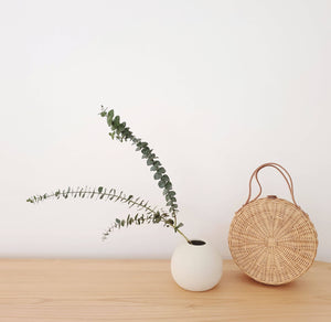 Rattan round bag with eucalyptus in vase